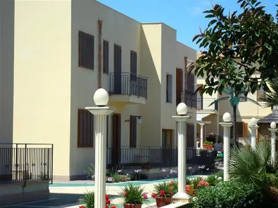 a building with white pillars and plants in front of it at Coral sea in San Vito lo Capo