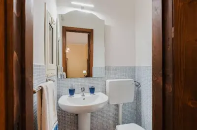 a white bathroom with a sink and a mirror at La casa di Anita nel cuore di Segesta in Calatafimi