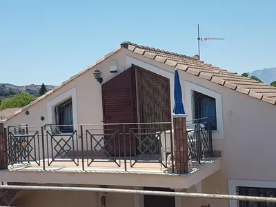 a house with a balcony with a blue umbrella at Mansarda Camelie via dei Normanni, 45 in Campofelice di Roccella