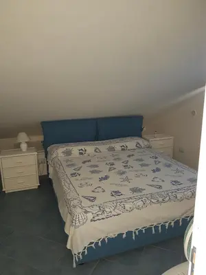 a bedroom with a bed with a blue head board at Mansarda Camelie via dei Normanni, 45 in Campofelice di Roccella