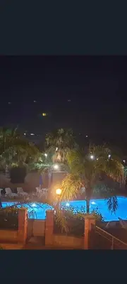 a view of a pool at night with palm trees at Mansarda Camelie via dei Normanni, 45 in Campofelice di Roccella
