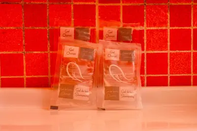 two plastic containers of soap in front of a red tiled wall at Casa Relax Mondello in Mondello