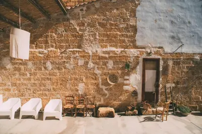 a room with white chairs and a brick wall at The Lighthouse in Trappeto