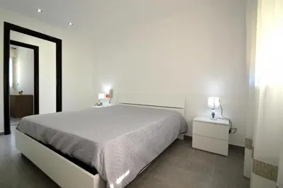 a white bedroom with a large bed and two lamps at Villa Bianca e Villa Arancio in Alcamo
