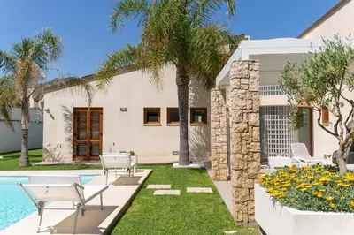 a villa with a swimming pool and palm trees at Villa Perla del Mare in Alcamo Marina
