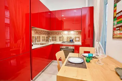 a kitchen with red cabinets and a wooden table with chairs at KMC suites - Red in Palermo
