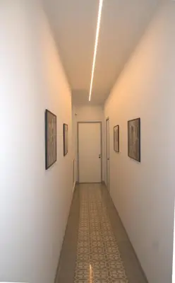 a corridor of a hallway with paintings on the walls at KMC suites - Red in Palermo