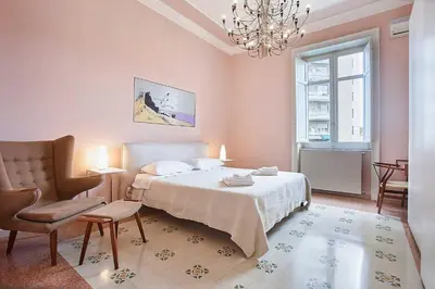 a bedroom with a bed and a chair and a chandelier at KMC suites - Purple in Palermo