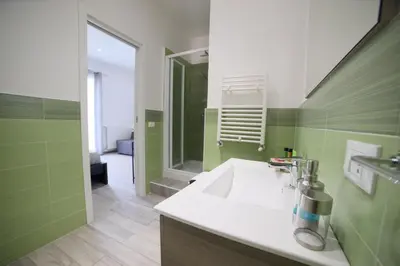 a green and white bathroom with a sink and a mirror at Cavour37 Rooms in Palermo