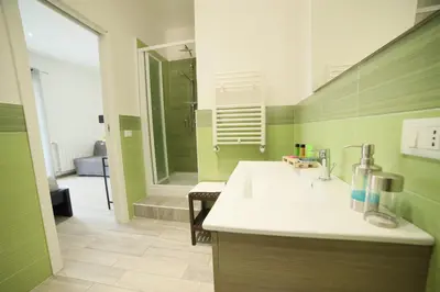 a green bathroom with a sink and a shower at Cavour37 Rooms in Palermo