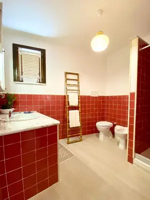 a red tiled bathroom with a toilet and a sink at La depandance di Villa Rosa locazioni brevi in Mondello