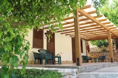a wooden pergola with chairs and a table on a patio at Hotel Grotticelli in Scopello