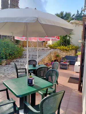 a table and chairs under an umbrella on a patio at Hotel Grotticelli in Scopello