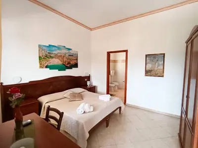 a bedroom with a bed and a table and a mirror at Hotel Grotticelli in Scopello