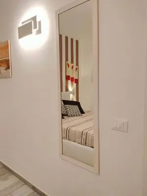a mirror in a white room with a bed at Appartamento Le Ginestre in San Vito lo Capo