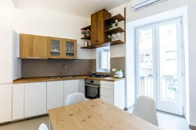 a kitchen with white cabinets and a wooden table at Loft Piazza Marina Family by DomuSicily in Palermo