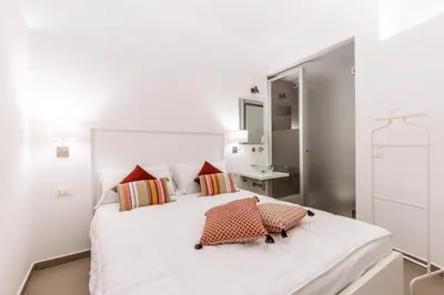 a white bedroom with a large white bed with red pillows at Loft Piazza Marina Family by DomuSicily in Palermo