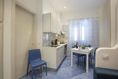 a kitchen with white cabinets and blue chairs and a table at Al Baglio in Castellammare del Golfo