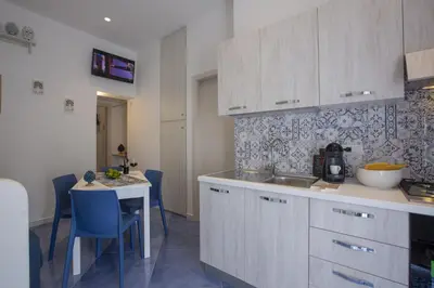 a kitchen with a sink and a table with blue chairs at Al Baglio in Castellammare del Golfo