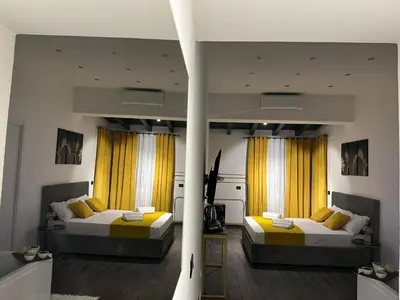 two beds in a room with yellow curtains at FUDDIA Room & Suite in Palermo