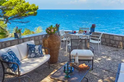 a patio with a table and chairs and the ocean at Villa Majus in Porticello