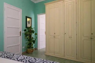 a bedroom with white cabinets and a green wall at Mille e una Notte / Station Apartment in Palermo
