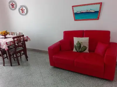 a red couch sitting in a living room next to a table at Mille e una Notte / Station Apartment in Palermo