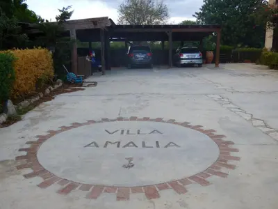 a blue car parked in a parking lot next to a tree at Villa Amalia - mansarda B&B in Cinisi