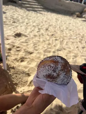 a hand holding a donut in front of a beach at Villa Agapanthus in Castellammare del Golfo