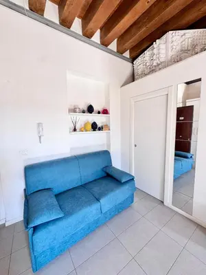 a blue couch in a white room with a door at Capo Loft in Palermo