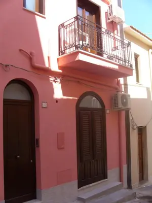a pink building with a balcony and a door at Casa di Cecilia in Castellammare del Golfo