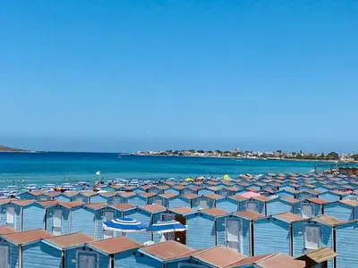 a beach filled with lots of umbrellas and the water at casa delle rose in Isola delle Femmine