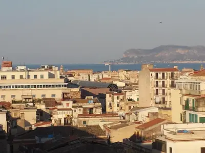 a city with buildings and the ocean in the background at Sky Sleeping in Palermo
