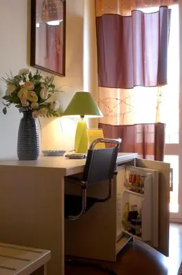 a desk with a chair with a lamp and a vase of flowers at Sky Sleeping in Palermo