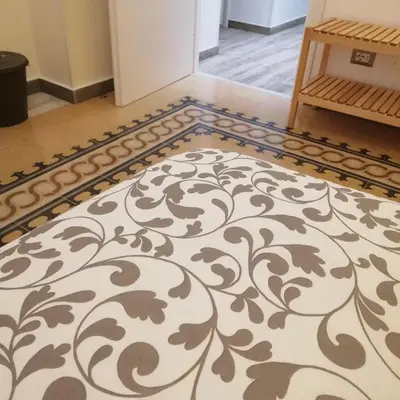 a rug on the floor in a room with a table at La Bella Balla-rò Rooms in Palermo