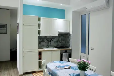a kitchen with white cabinets and a table with flowers on it at La Bella Balla-rò Rooms in Palermo