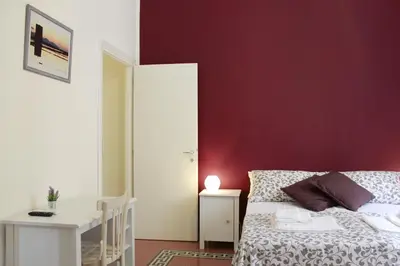 a bedroom with a bed and a red wall at La Bella Balla-rò Rooms in Palermo