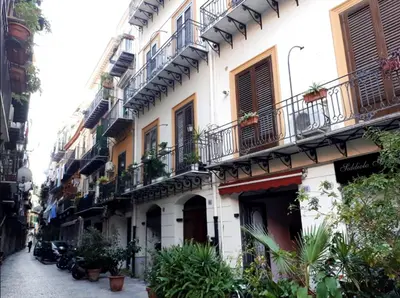 a building with balconies and plants on a street at David house alla Vucciria in Palermo