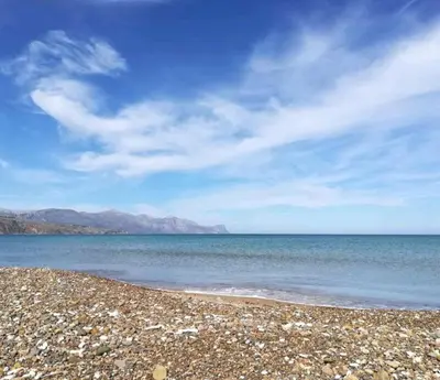 a rocky beach with the ocean and mountains in the background at Casa Vacanze Sea-Life in Alcamo Marina