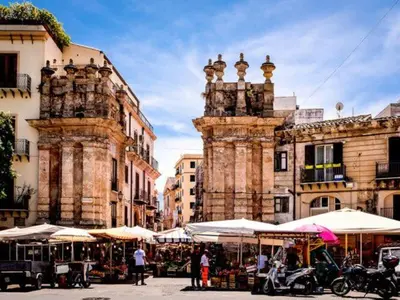 a group of buildings with tables and umbrellas in a city at Il Sonaglio in Palermo