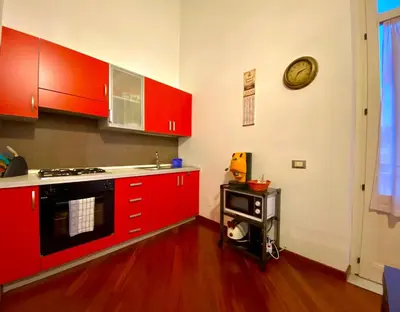 a kitchen with red cabinets and a clock on the wall at Elegante appartamento in centro in Palermo