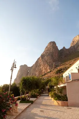 a street with a mountain in the background at Cala Dell'Arena in Macari