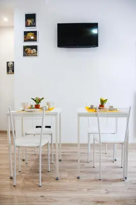 a white table and chairs with a television on a wall at Darrè in Palermo