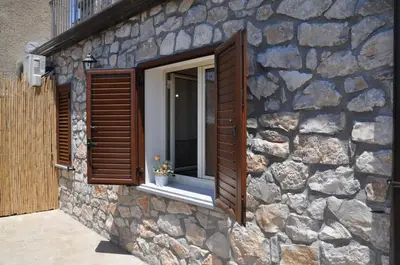 a stone building with a window with wooden shutters at Villetta in Centro Storico in Caccamo