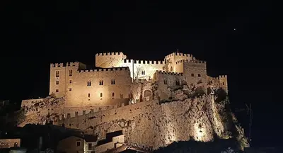 a castle on top of a mountain at night at Villetta in Centro Storico in Caccamo