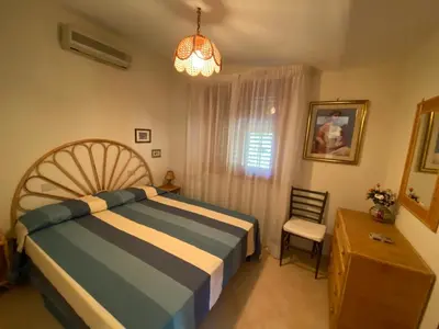 a bedroom with a bed and a chair and a window at Villa Rosada in Castellammare del Golfo