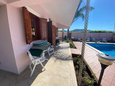 a patio with a table and chairs next to a pool at Villa Rosada in Castellammare del Golfo