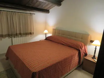 a bedroom with a bed with a red bedspread and two lamps at Casale Giulietta in Scopello