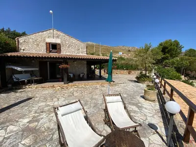 a patio with two chairs and a building at Casale Giulietta in Scopello
