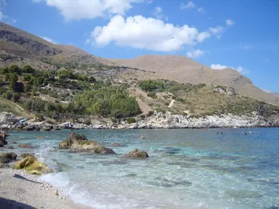 a beach with people swimming in the water at Villa Mediterranea in Scopello